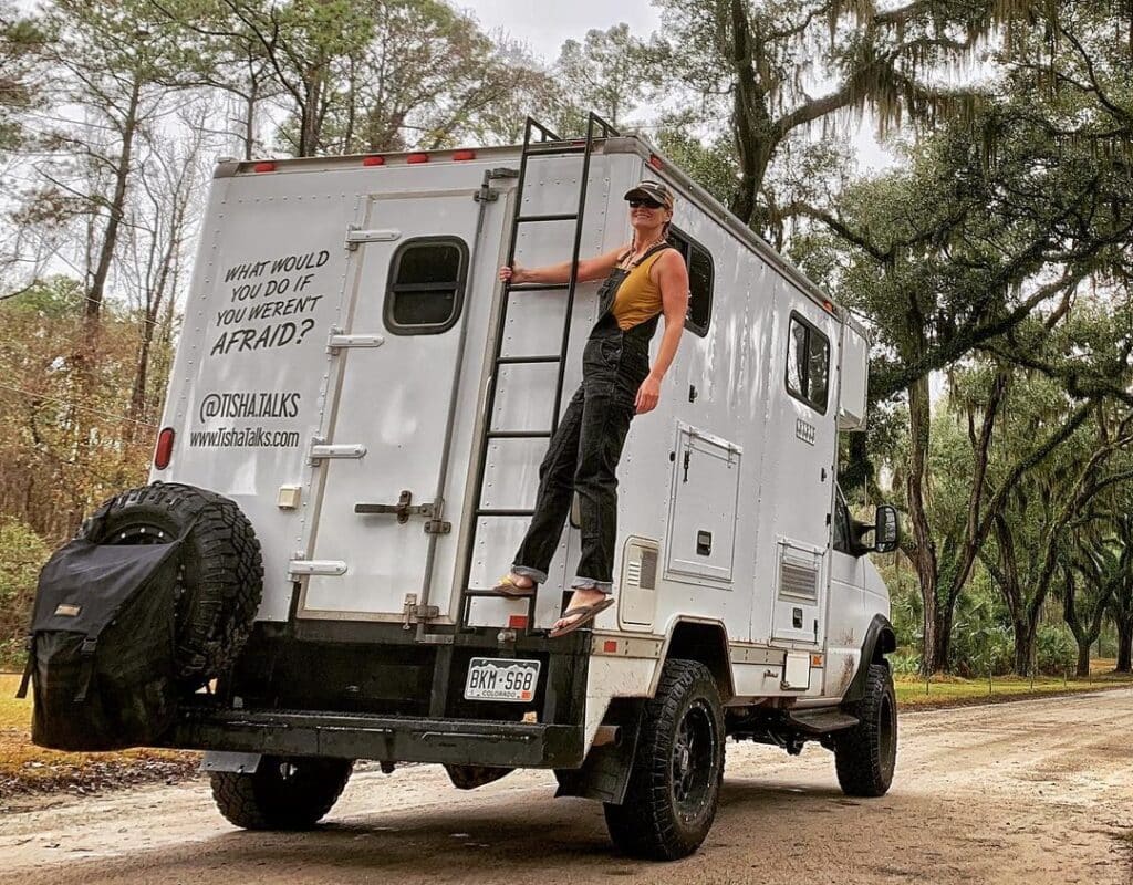 @tisha.talks Woman standing on the rear ladder of her box truck camper