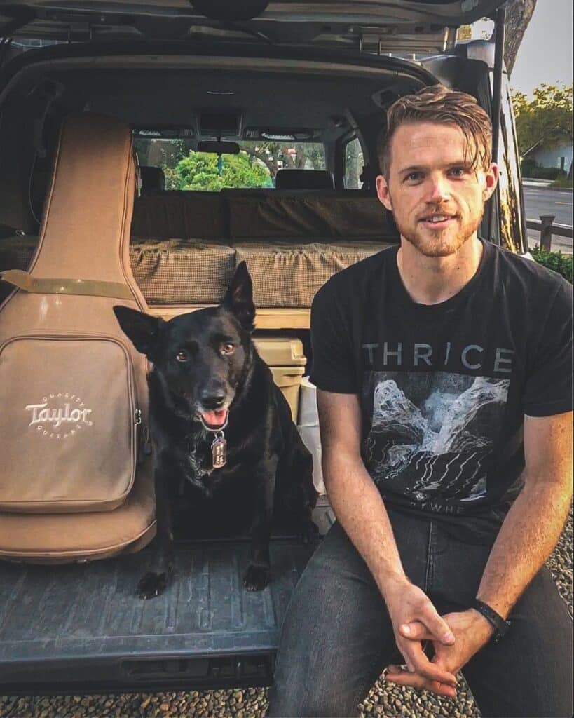 @sagetraveling Sage sitting at the back of his DIY honda element conversion with his black dog