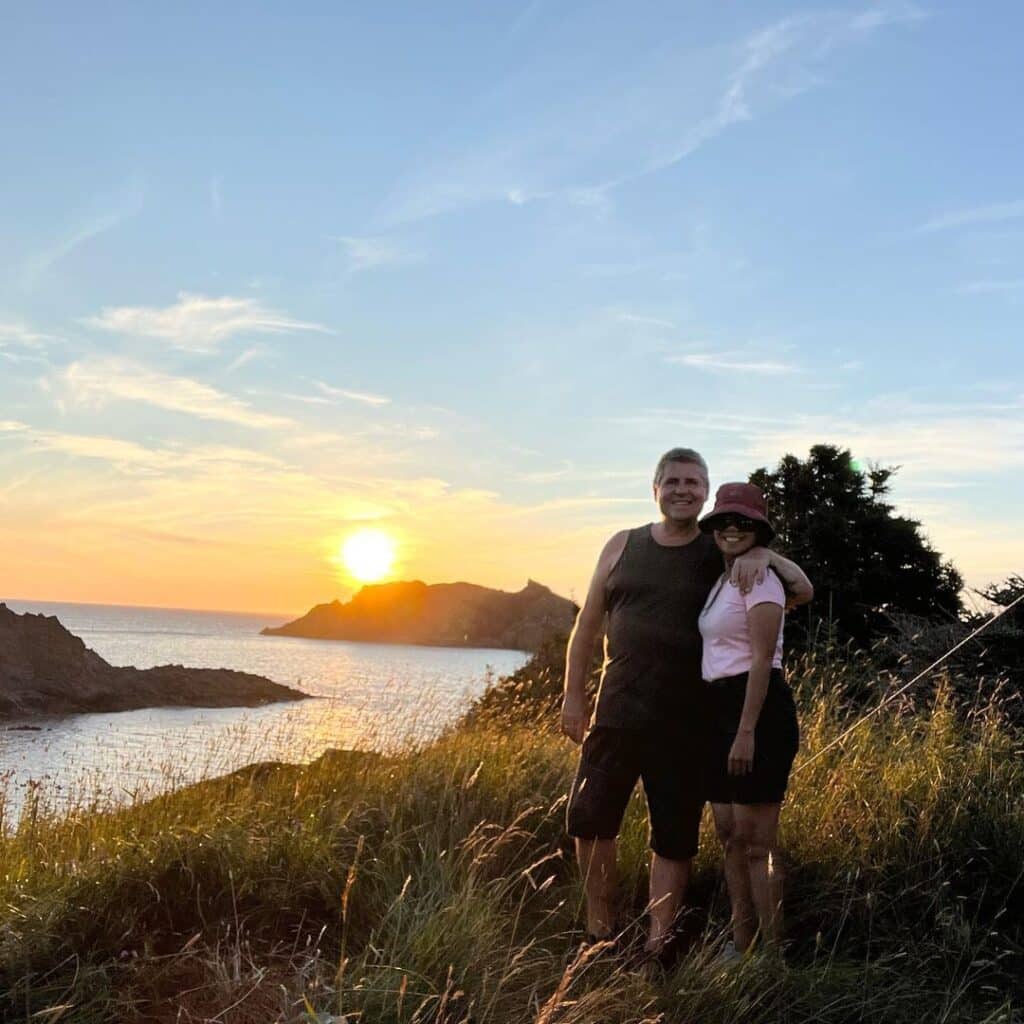 Lawrence and Airiel at the beach during sunset enjoying life living in a Toyota Sienna tiny home