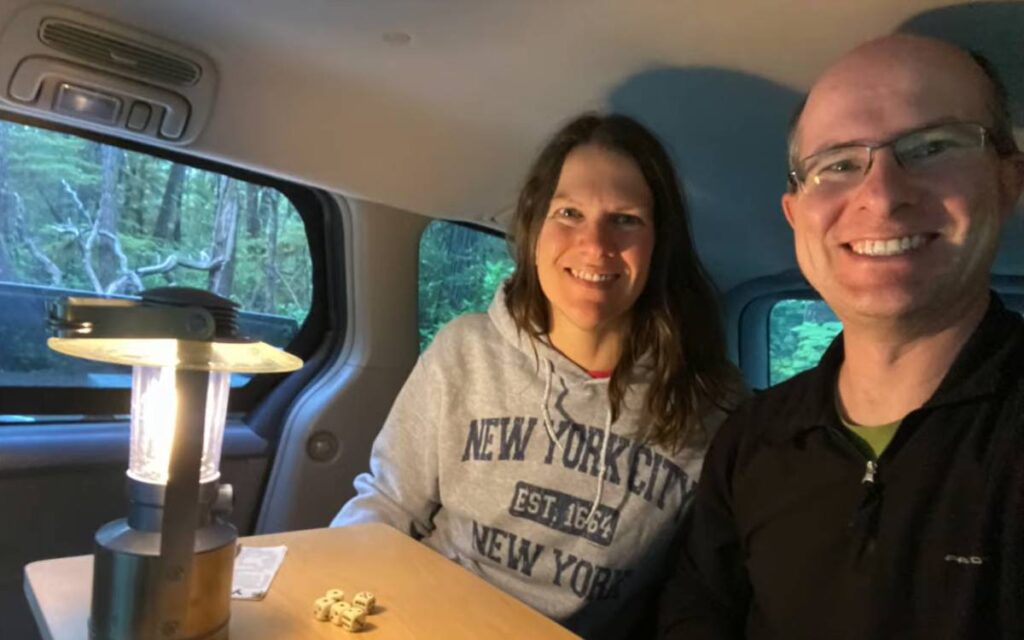 Mike and Rachel smiling at the camera while sitting inside their Toyota Sienna camper