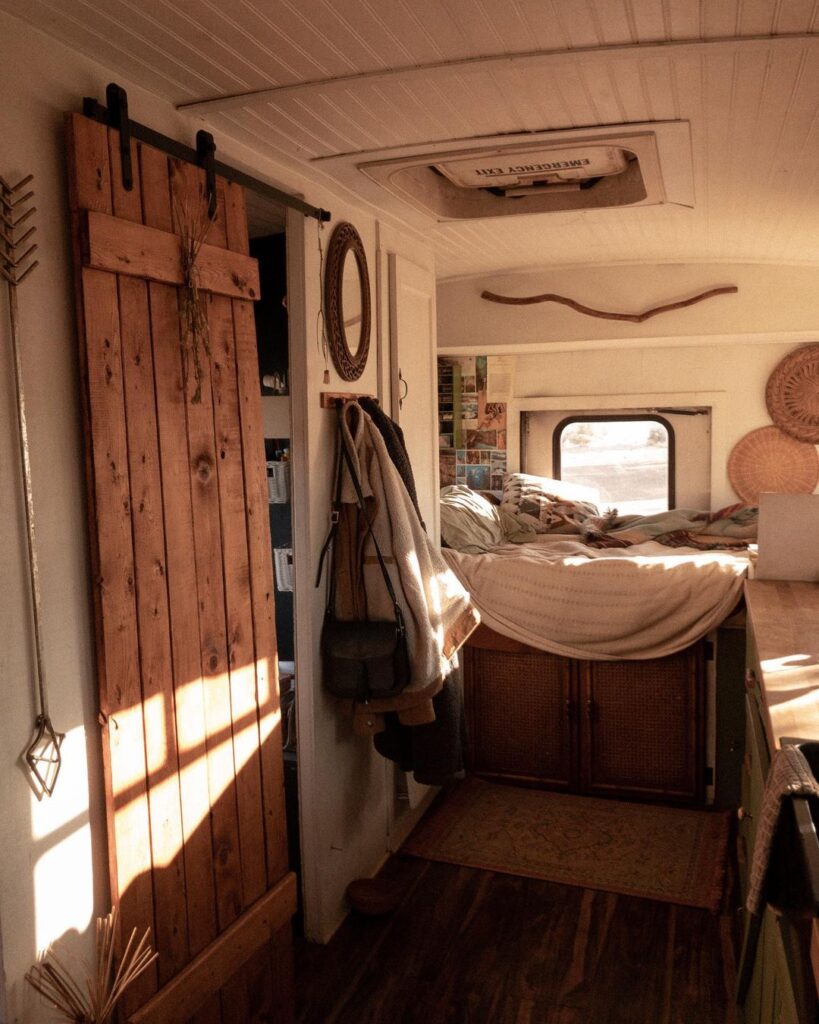 @growingslowandwild shuttle bus camper conversion cozy interior with a bed next to a closed window