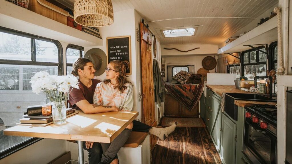 @growingslowandwild bus conversion with dinette, couple sitting inside enjoying each other's company