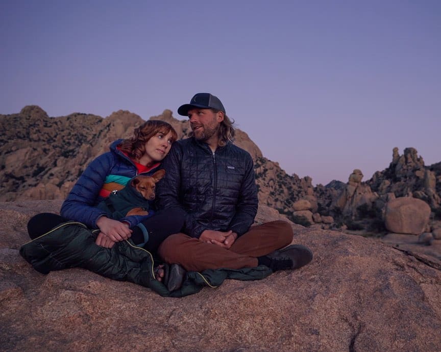 @ourwaytoroam Savannah and Drew sitting on a rock in a desert, enjoying their shuttle bus conversion van life