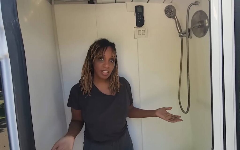 A woman standing in her shower inside her camper van