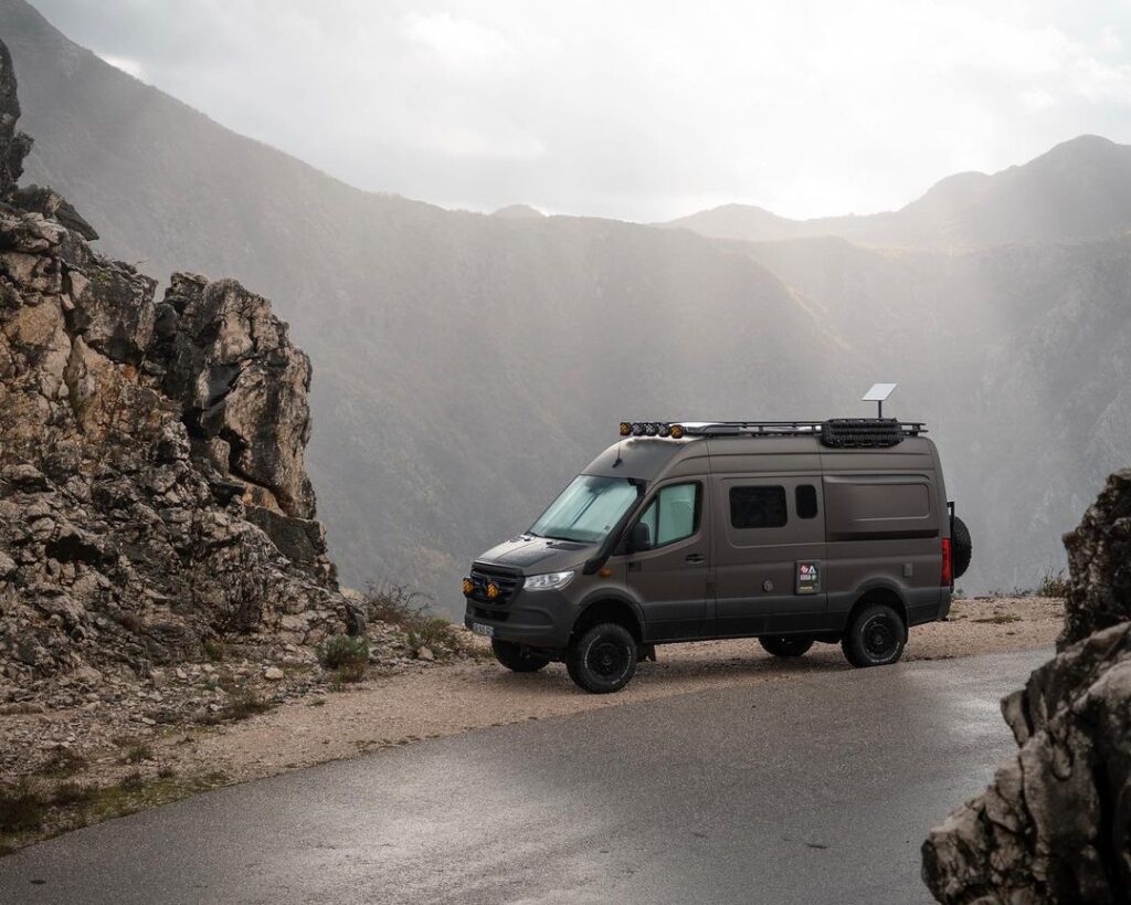 Campervan parked on the side of the road with beautiful mountains in the background