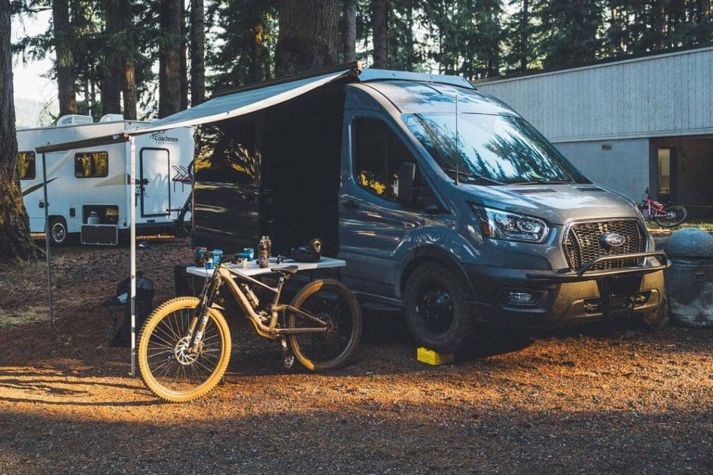 Campervan with open side door and an awning parked in the forest