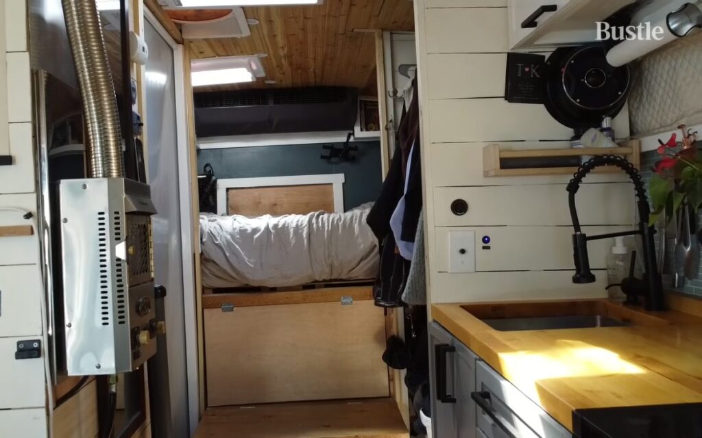 Deeanna's shuttle bus conversion, inside is a raised queen-sized bed next to a closet and kitchen