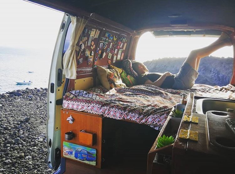 Man looking outside while lying on campervan bed