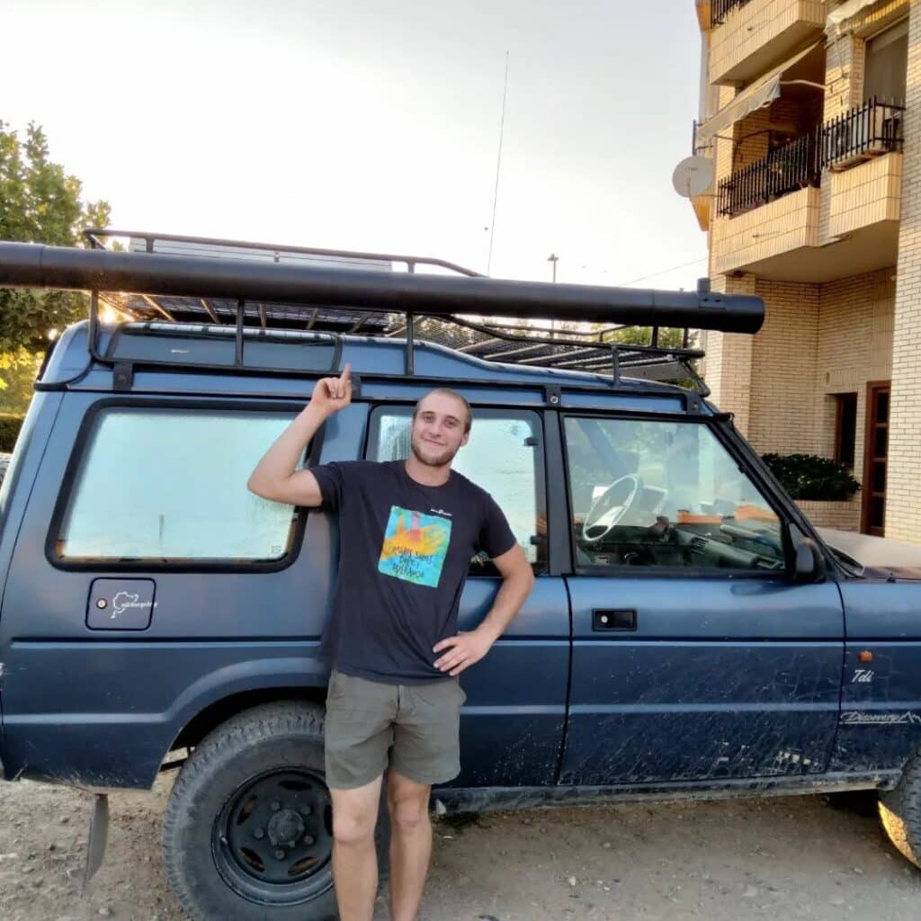 Man pointing finger at his PVC shower on the roof of his land rover camper