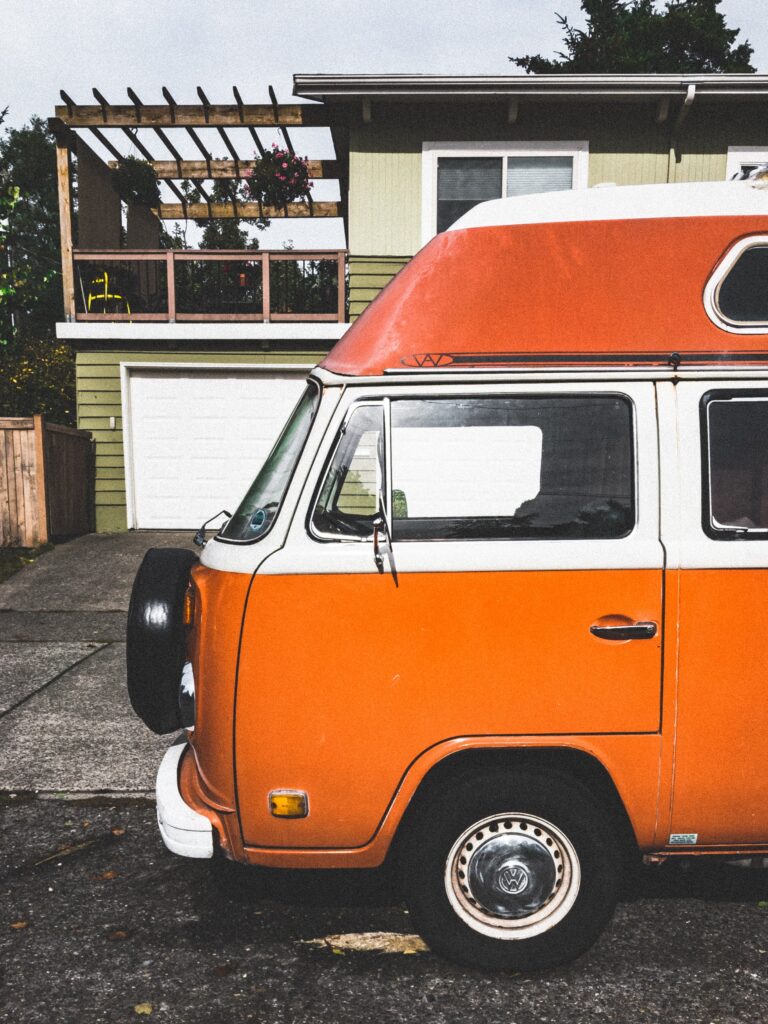 Orange and white camper van parked in front of a house