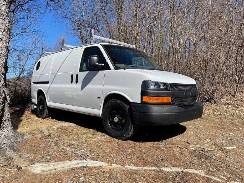 White camper van parked near trees with no leaves