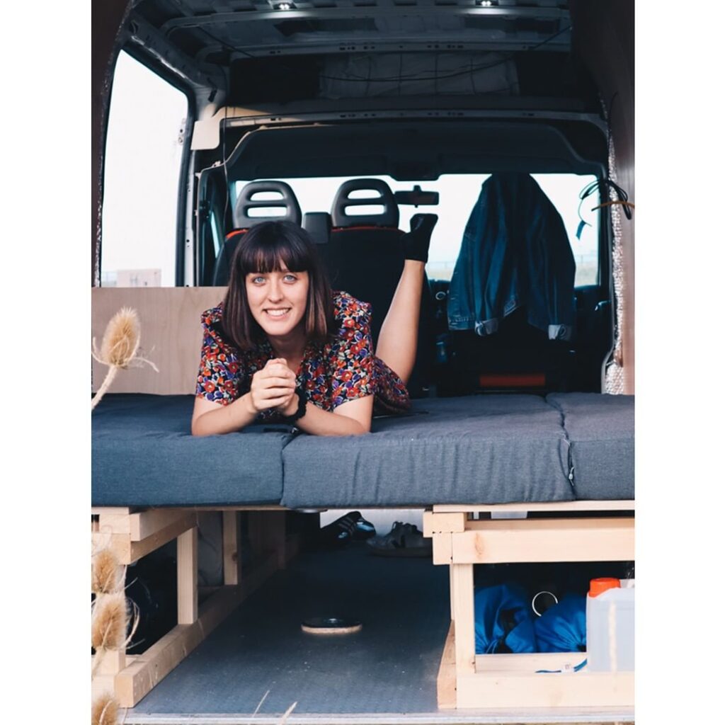 Woman lying down on her convertible bed in her campervan