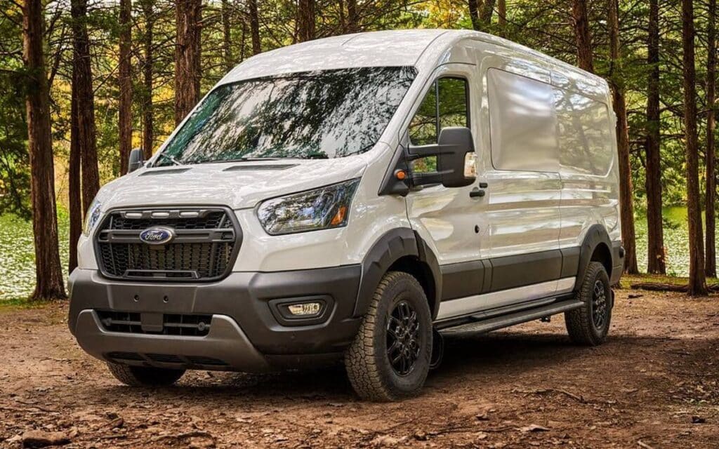 @cmarzen_209 White ford transit van parked in the forest near a lake