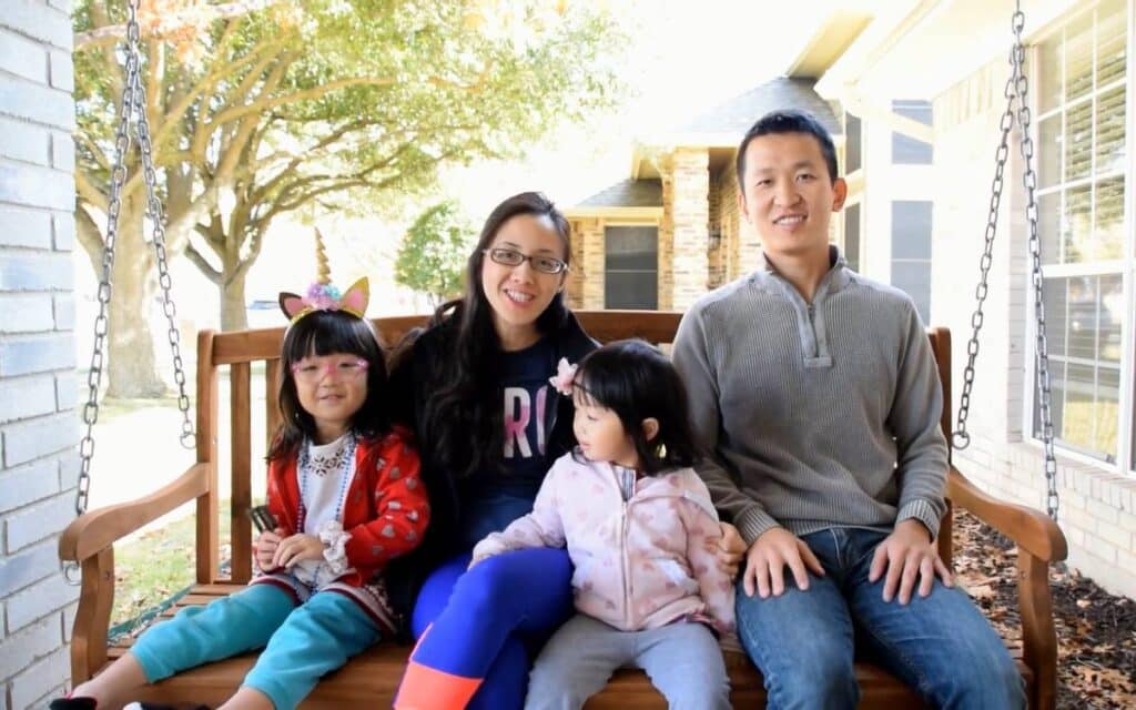 @fullnester9456 A happy family of four sitting outdoor in a wooden porch swing