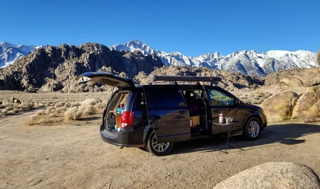 @hollywoulddream Black minivan camper from Lost Camper Vans with mountains in the background