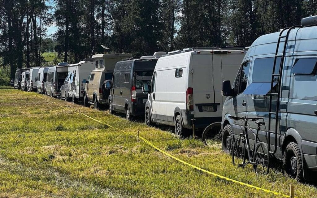 @jouleadventures Long line of large vans parked in a grassy field
