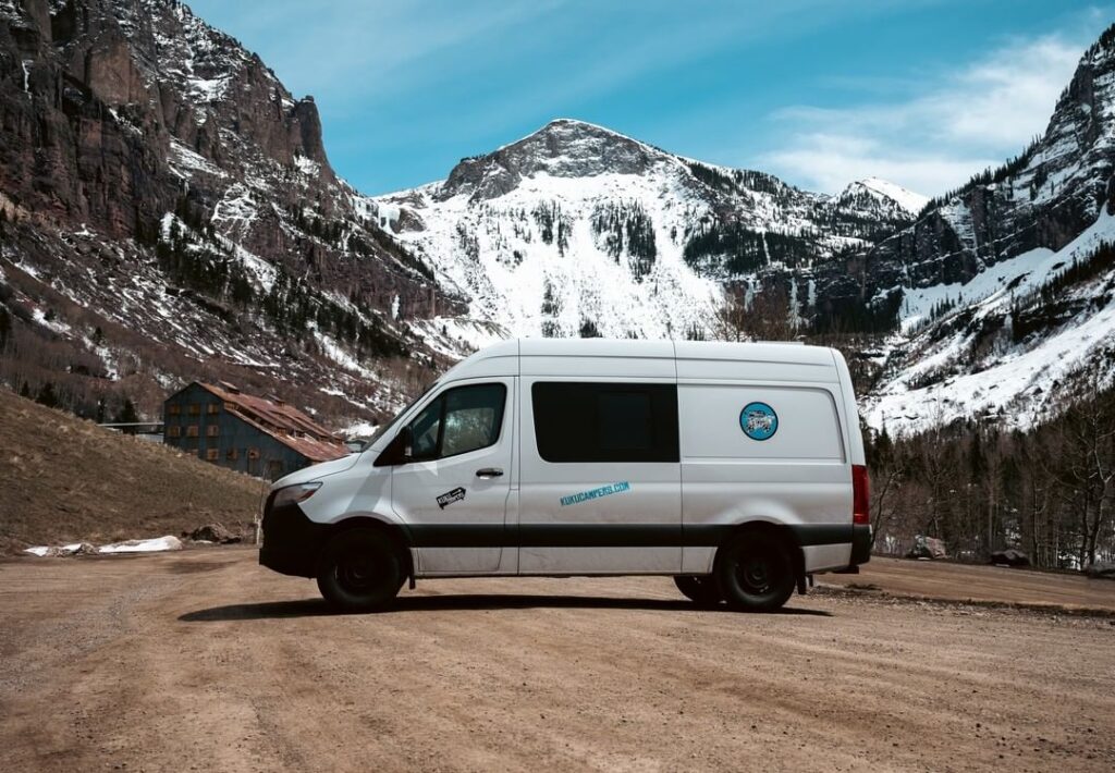 @kukucampersusa campervan rentals white camper parked on dirty road with snow-capped mountain view in the background
