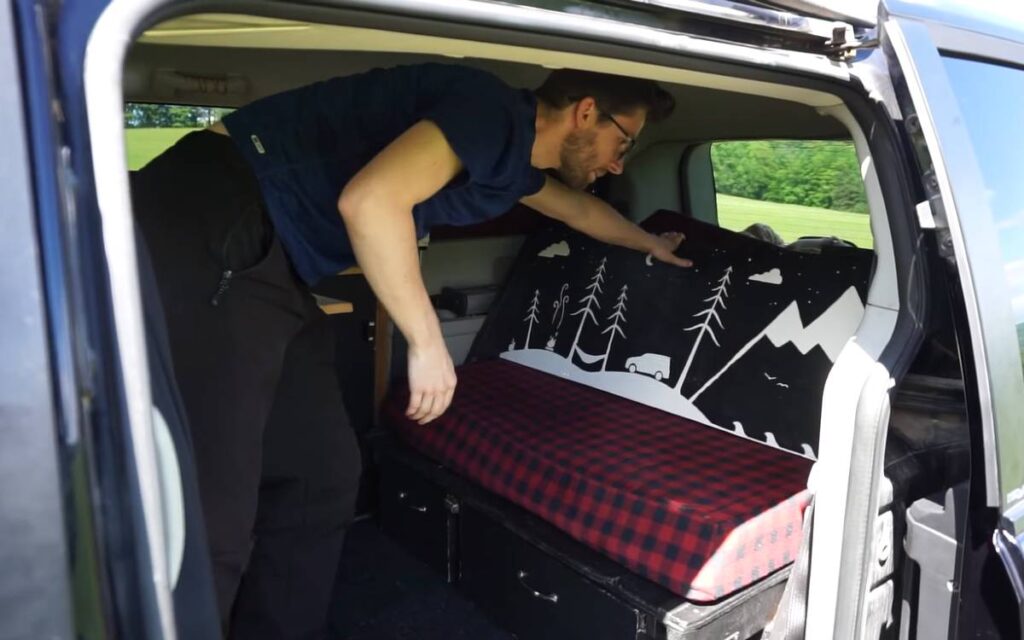 @nickandmaela Nick showing how his sofa converts into a bed in his dodge grand caravan minivan camper conversion