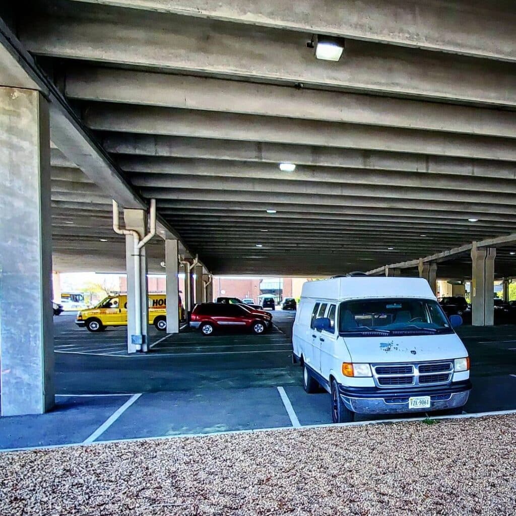 @nomadicandsporadic White camper van stealth camped in a mall parking garage