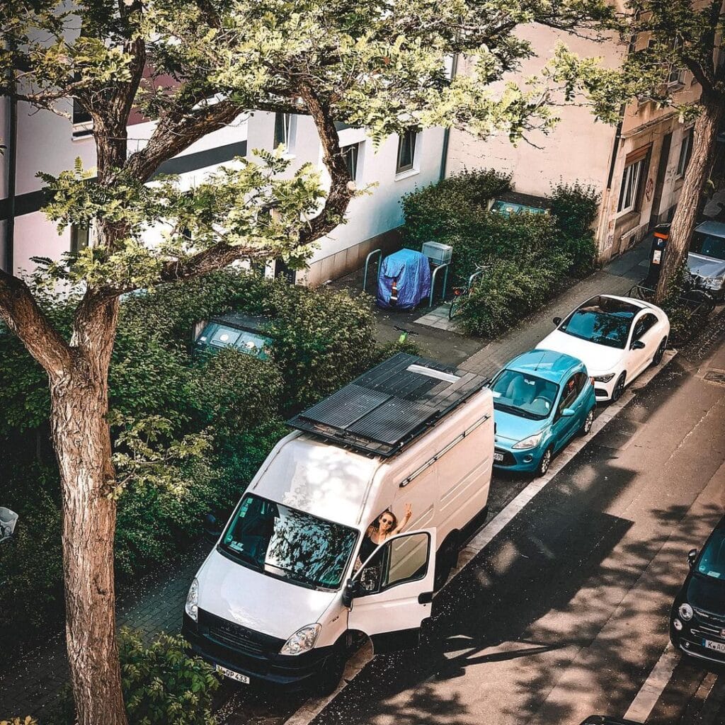 @road.birds Woman in her white campervan overnight camping in the city