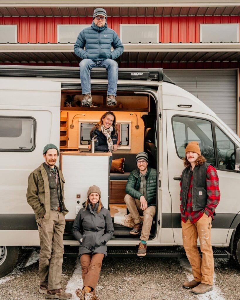 @tierratravelervans six people posing for a photo in a white camper from Tierra Traveler campervan rentals