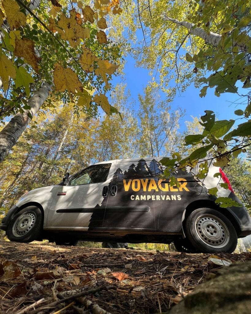 @voyagercampervans Ground-level view of campervan rentals van surrounded by trees