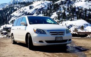 A honda odyssey camper conversion parked at a snowy mountain pass
