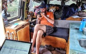 vanlifers hunched over phones and spreadsheets inside a van asking how much does van life cost