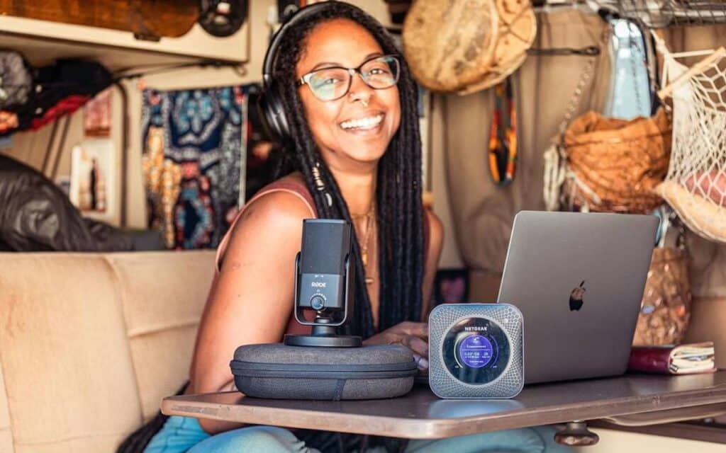 @irietoaurora A happy digital nomad woman working inside her van using her laptop and other modern devices