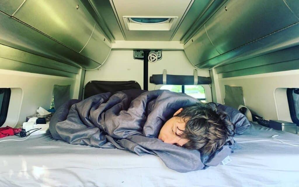 @liberte.cherie_ Man comfortably lying on bed in his camper van