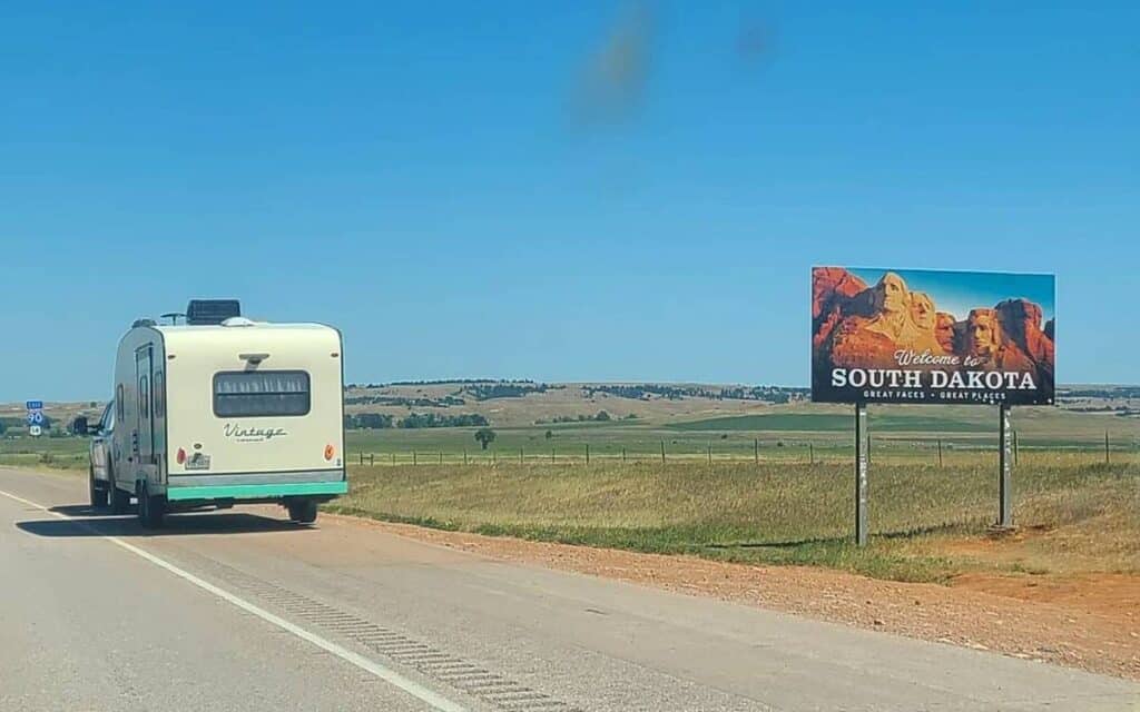 @meiketheresa White RV on the road next to a road sign that says welcome to South Dakota