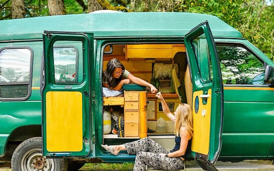 @green.van.go Two women having fun camping in a green campervan