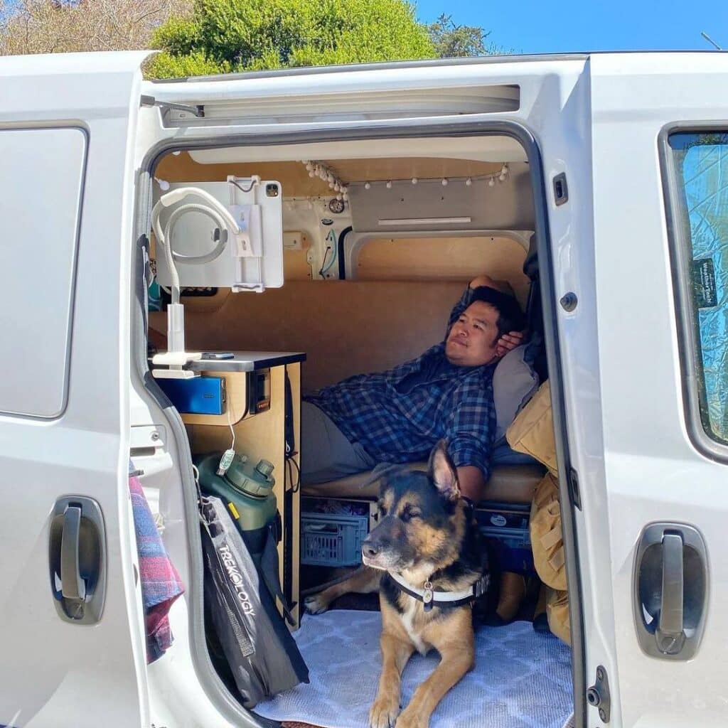 @gwinny.the.camper Man lying inside minivan with his dog, camper van conversion from Cascade campers