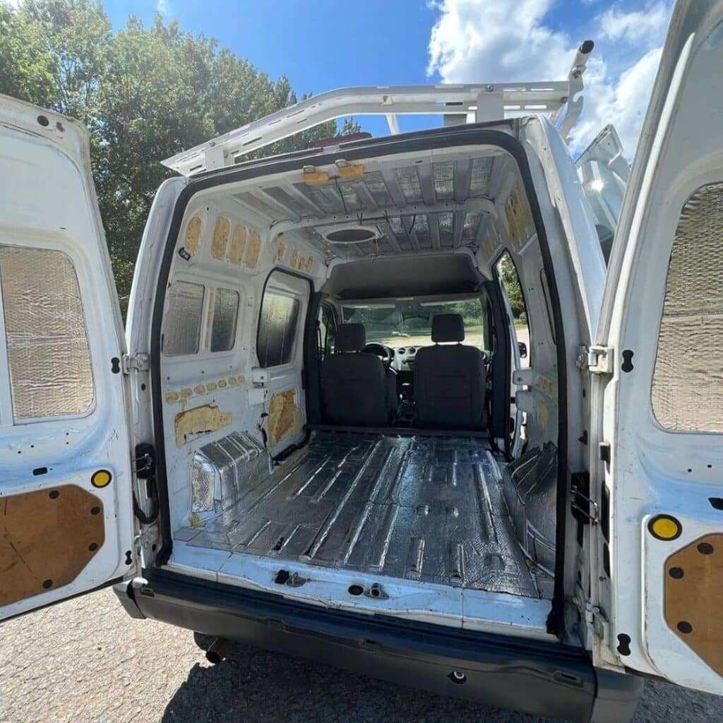 @justatleasttry Back of a white minivan camper with open rear doors