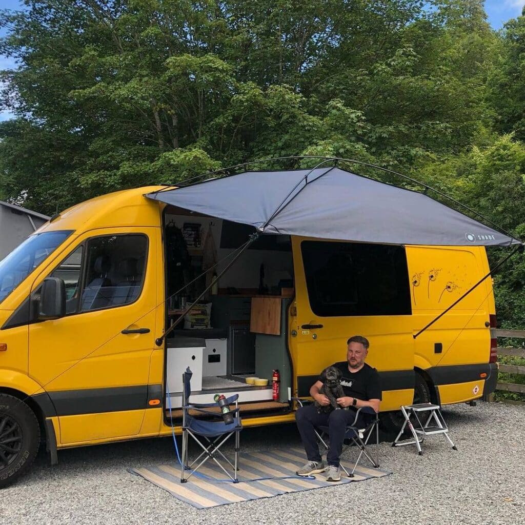 @melloyellovan Vanlifer sitting in a camping chair under van awning