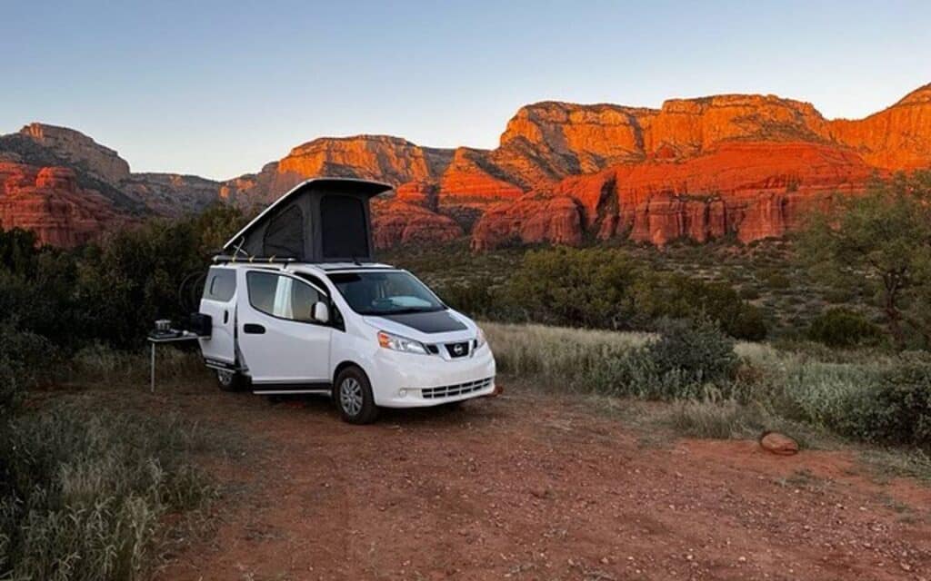 @recon_campers White Nissan NV200 campervan parked in the desert