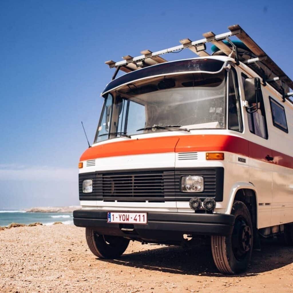 @wildeweg.508 Freshly painted van with surfboard racks on the roof parked at the beach