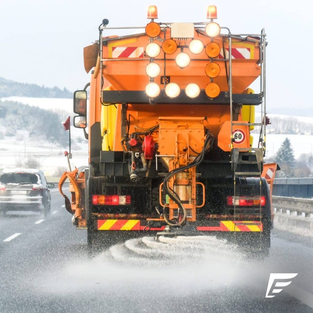 @endurance Orange highway maintenance truck spreading salt on asphalt road