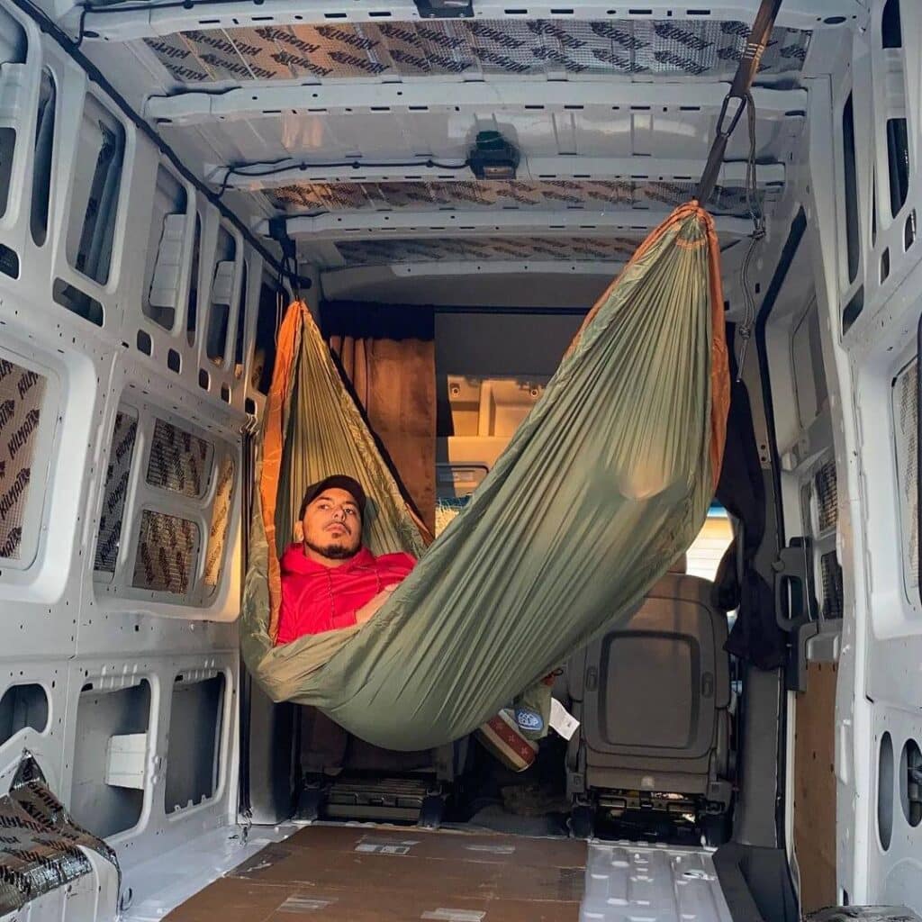 @goldenboyvanlife Man resting in a hammock inside his campervan