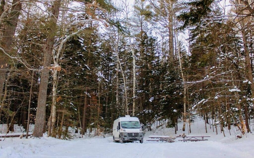 @ramblinvan_ White camper van parked at a campsite during winter