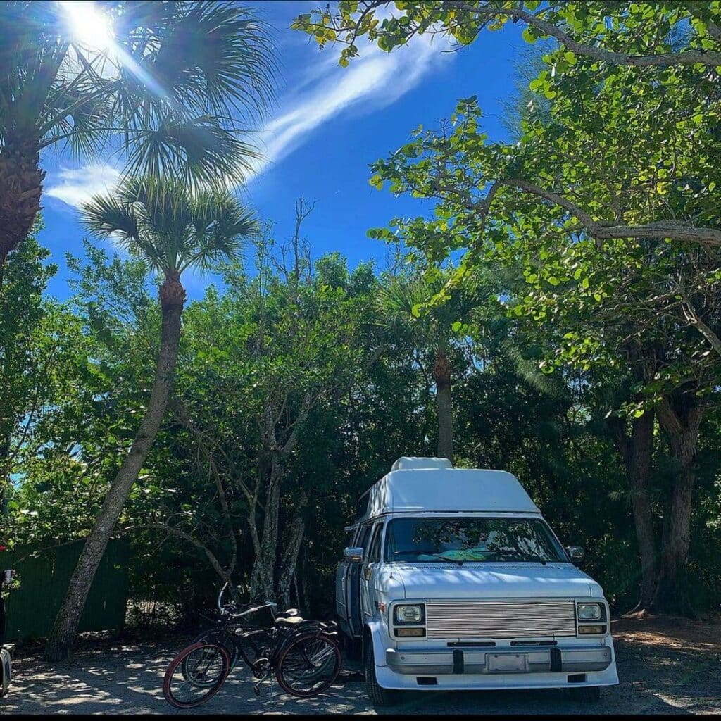 @swamp.wizards White campervan parked under trees, camping in summer