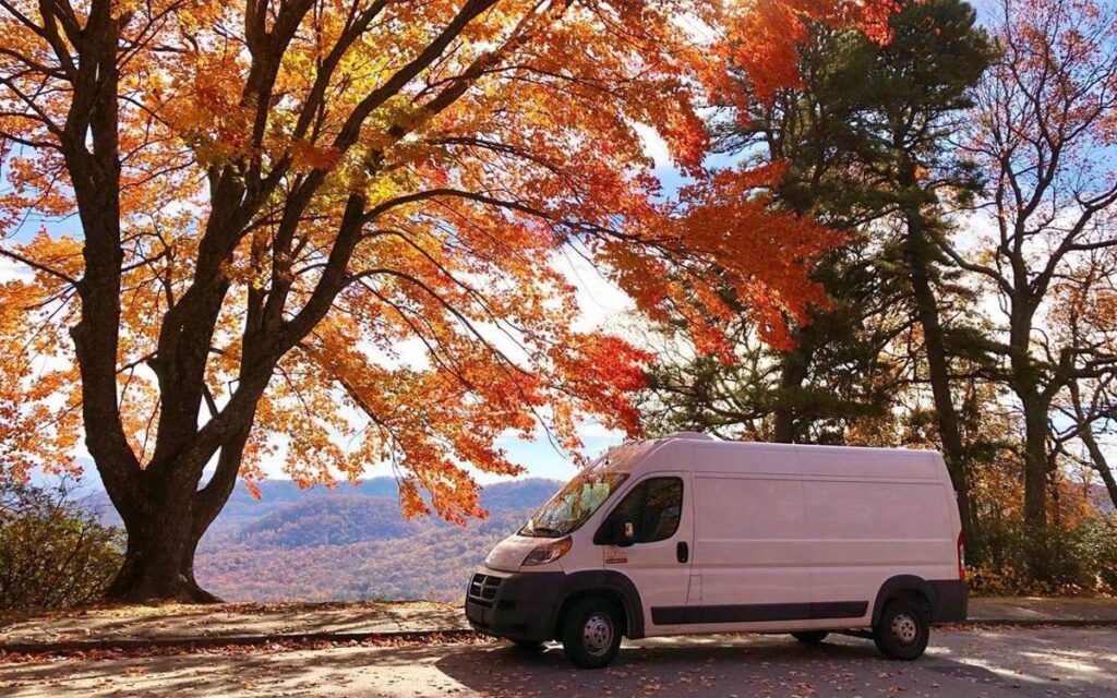 https://gnomadhome.com/wp-content/uploads/2023/04/@wandacanwander-White-campervan-parked-under-a-tree-with-brilliant-fall-color-leaves-at-the-park-1024x640.jpg