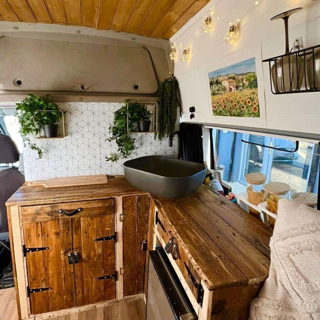 @where_to_wander_ L-shaped kitchen with hanging plants inside a campervan