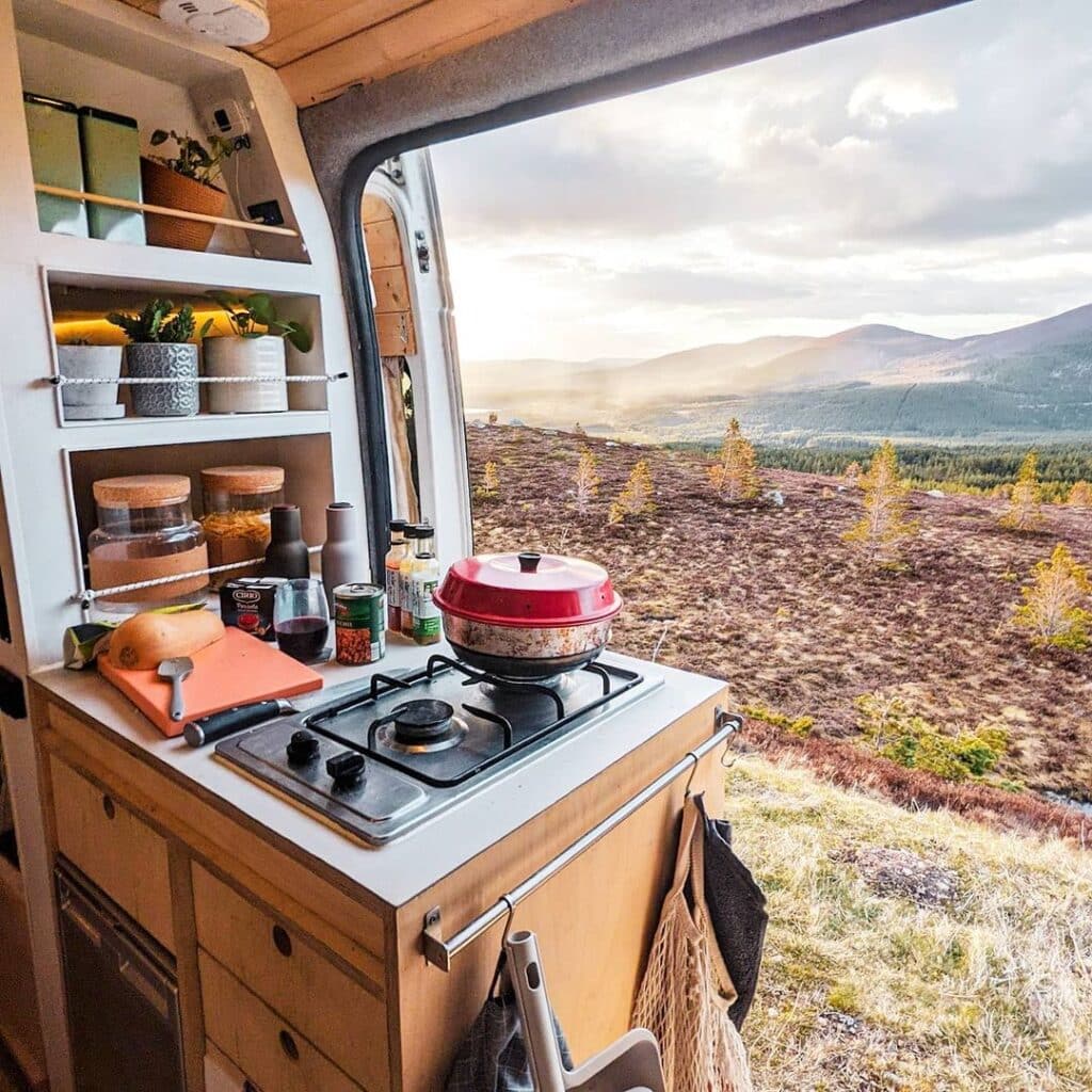@whitevanplan Camper kitchen by the door with scenic view of mountain against cloudy sky