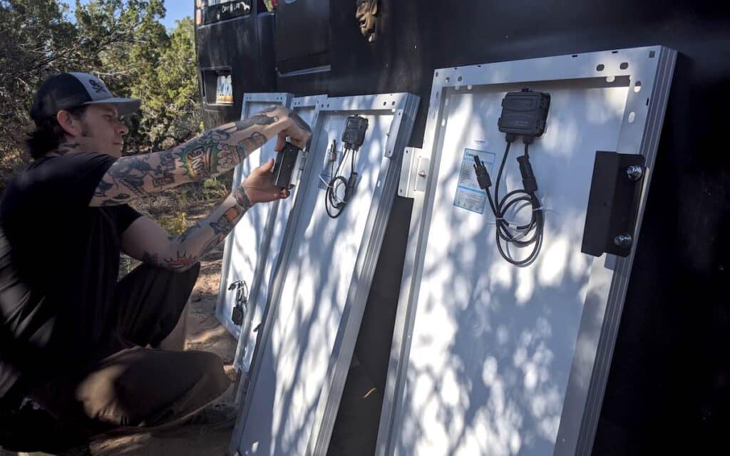 man examining the backs of his solar panels while contemplating his system size