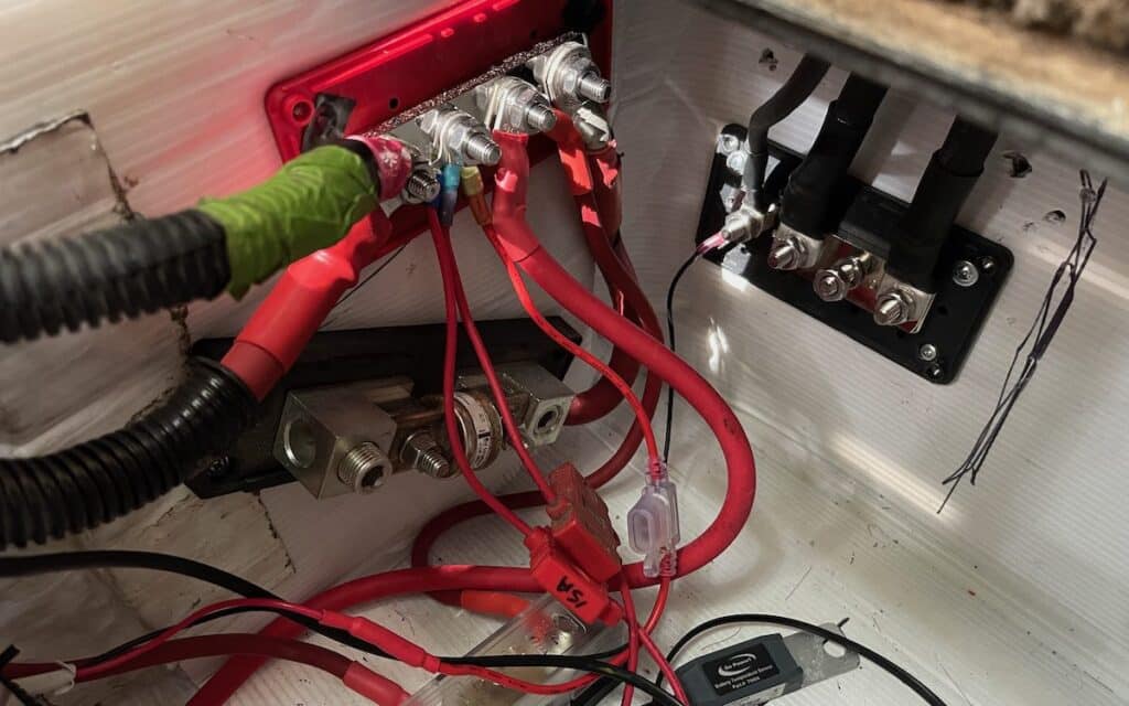 electrical wiring hooked up to bus bars and fuse blocks inside an rv battery bay