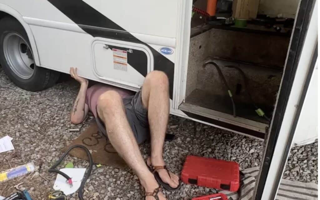 john from gnomad home cleaning up the wiring underneath an rv
