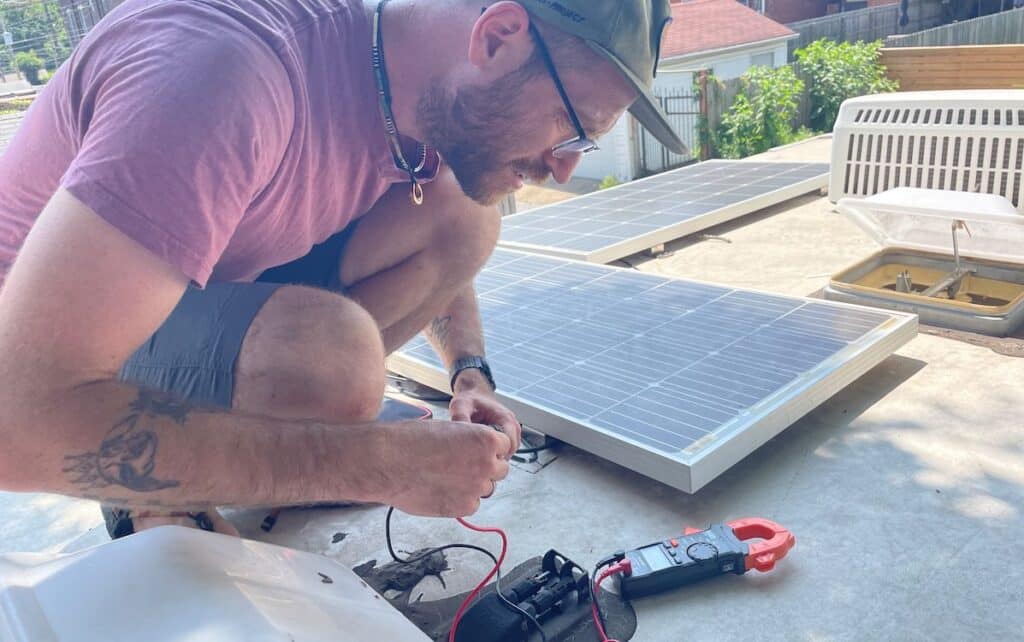 John from gnomad home on the roof on an RV testing solar panel voltage with a multimeter