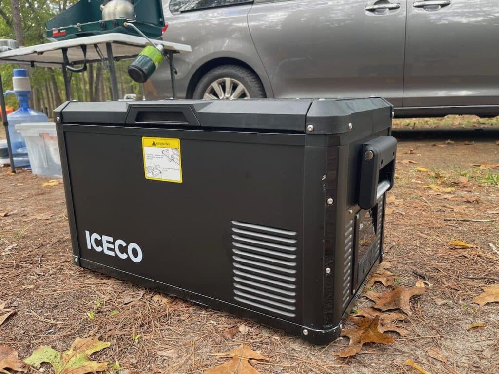 iceco vl35 pros refrigerator at a campsite with a van and camp kitchen setup in the background