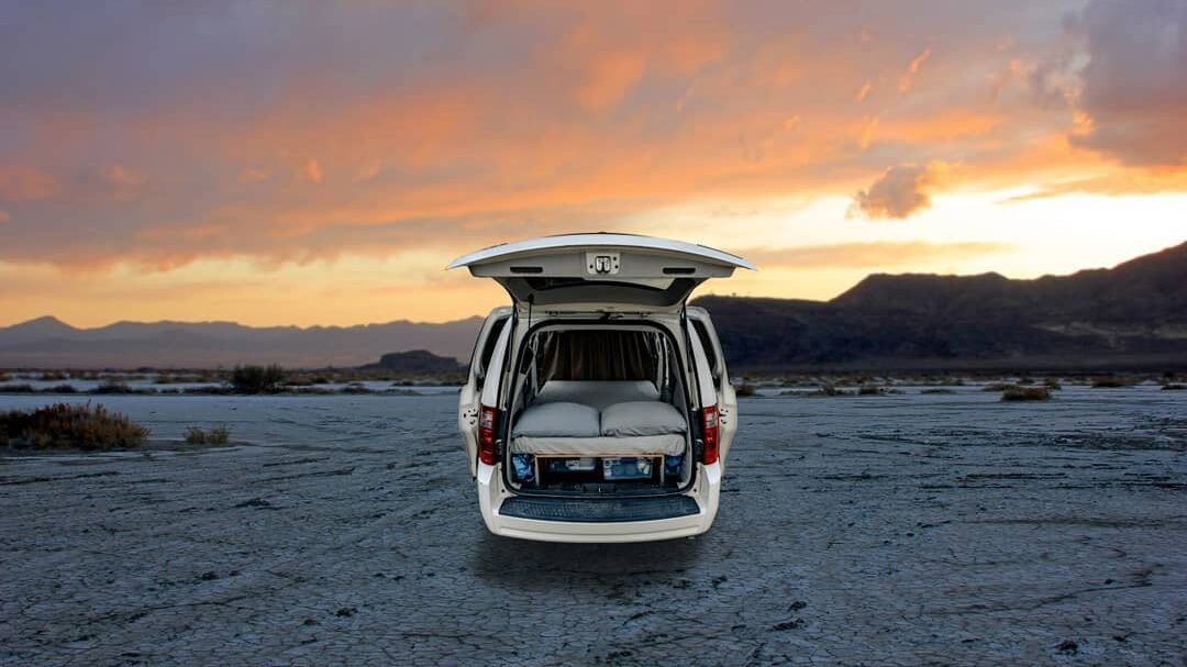 @aiyrecampers rear view of campervan with open rear doors, parked in a desert at sunset